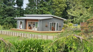 A modern single-story house with a covered porch, large sliding glass doors, and a well-maintained garden.