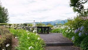 A garden pathway leading to a gazebo with steps, surrounded by lush greenery and flowers.