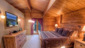 Un dormitorio de cabaña de madera con cama, cómoda y televisor en la pared.