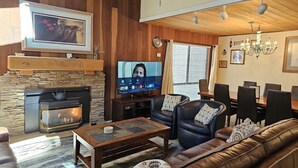 A cozy living room with a fireplace, leather sofa, and a television mounted on the wall.