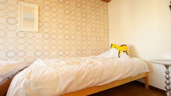Una cama bien hecha con edredón blanco y una almohada decorativa con un animal amarillo.