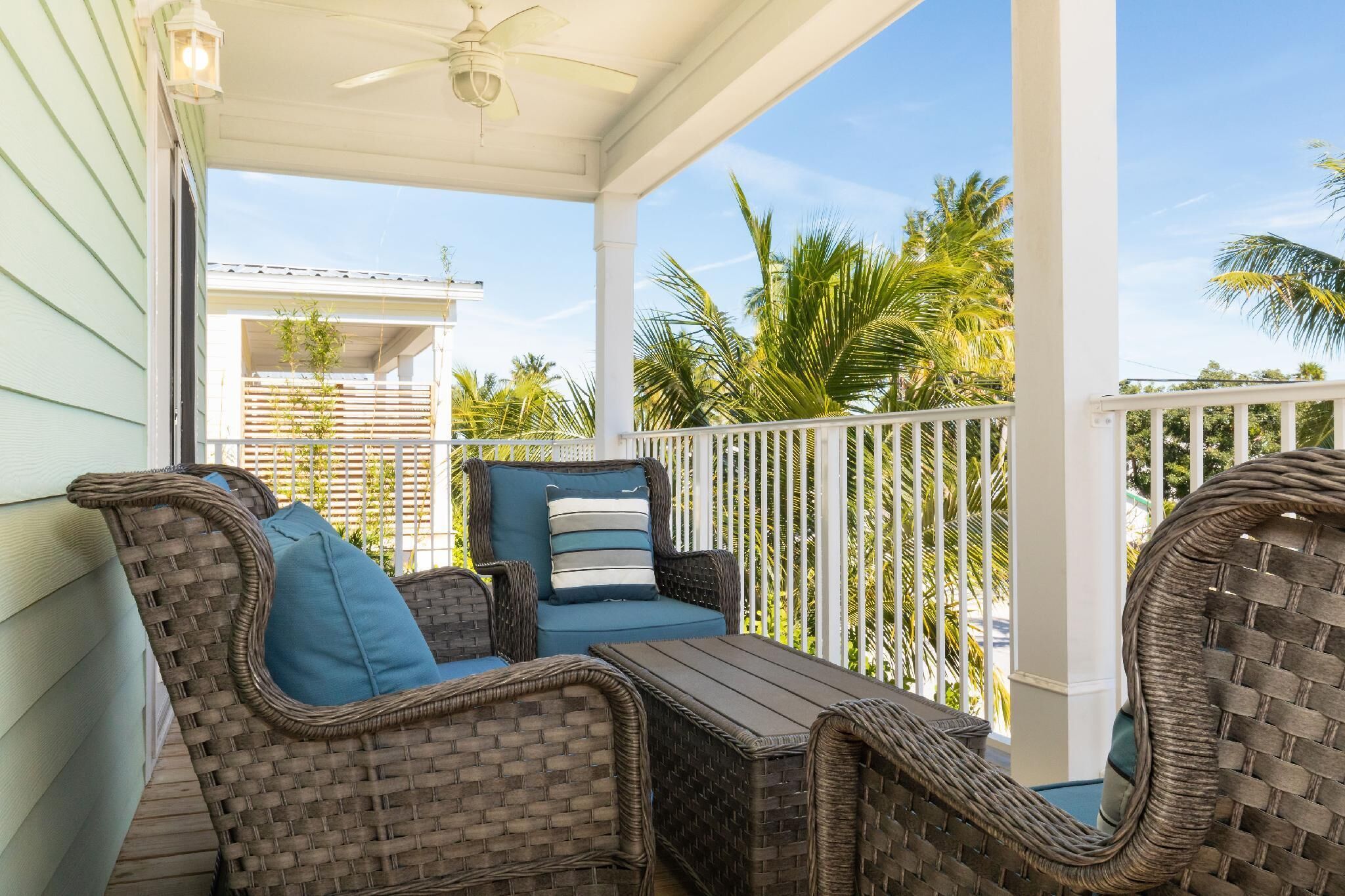 A covered porch with wicker furniture and a ceiling fan.