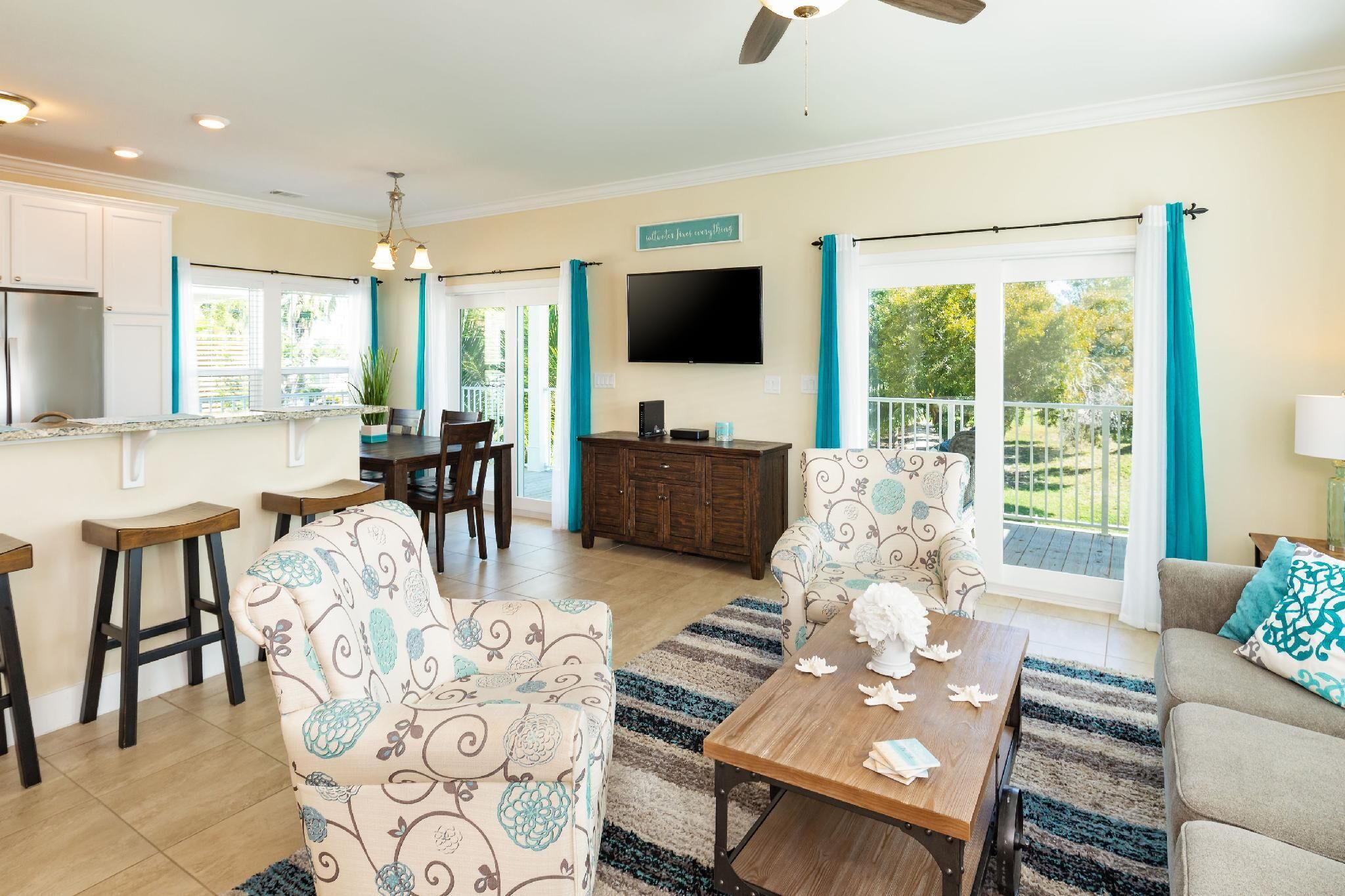 A spacious living room with a dining area, a kitchen, and a balcony with a TV.