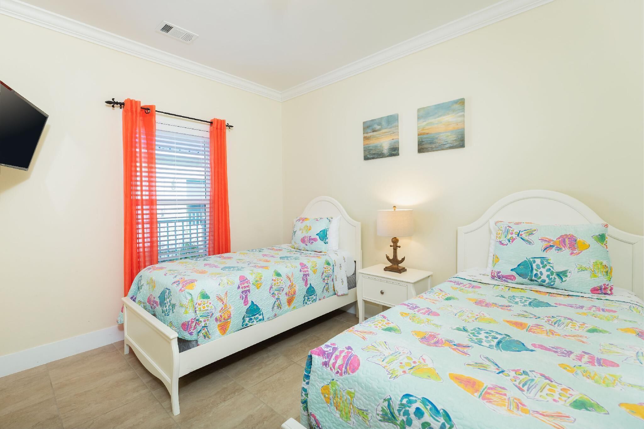 A bedroom with two beds, a TV, and a window with orange curtains.