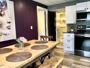 Enjoy meals with family and friends at the dining table, surrounded by modern appliances and a beautiful abstract art piece.