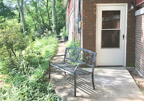 Situated near a serene building, this outdoor bench invites relaxation amidst lush greenery and a well-manicured path.