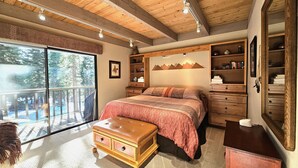 A bedroom with a large bed, wooden ceiling, and a view of the outdoors.