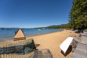 Une plage avec une promenade en bois menant à l’eau, une chaise longue blanche et un filet de pêche.