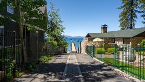 A paved pathway leading to a stone building with a green roof, surrounded by a fence and trees. - Walk to Beach | Pet-Friendly | Deck | BBQ (Zephyr Cove)