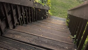 Eine Holztreppe führt zu einem Steg über dem Wasser, im Hintergrund ein Sonnenuntergang.