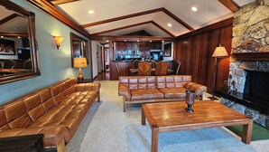 A spacious living room with leather sofas, a coffee table, and a stone fireplace. - Beachside Bungalo | Deck | BBQ (Kings Beach)