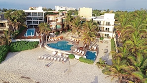 A resort with multiple swimming pools, sun loungers, and palm trees. - Hotel Secreto (Isla Mujeres)