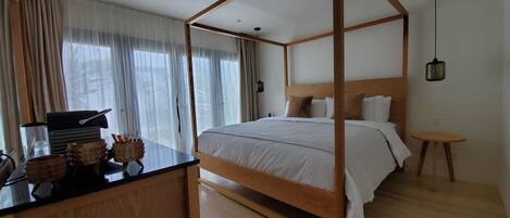 Ein Schlafzimmer mit einem hölzernen Himmelbett, einem kleinen Nachttisch und einem Schreibtisch mit Lampe und Getränkehalter.