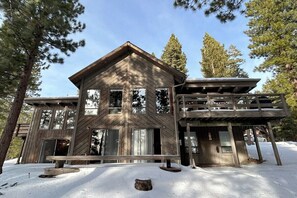 Surrounded by pine trees, this cabin-style building features a welcoming entrance with large windows and a covered porch.