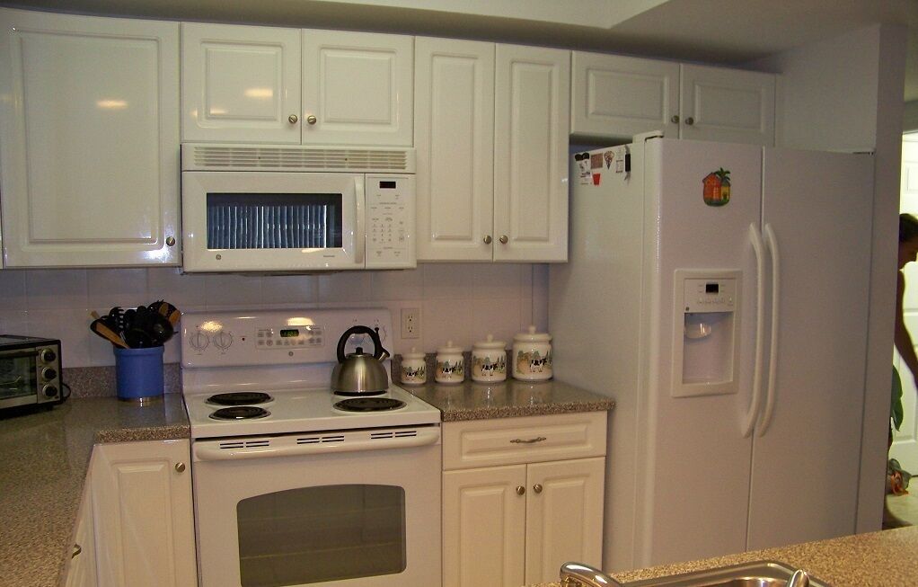A kitchen with white cabinets, a microwave, a stove, and a refrigerator.