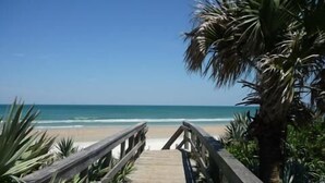 A wooden boardwalk leading to a beach with palm trees and ocean views. - Sunny 3BR/ 2bath w/ Hot Tub~Beach Access + Pool + Tennis + BBQ + Gated Community (New Smyrna Beach)