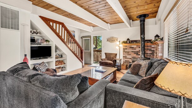 Un salon avec une cheminée, un escalier et un téléviseur.