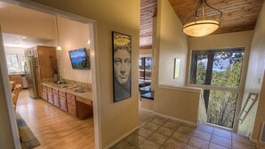 A modern kitchen with wooden cabinets, a built-in island, and a large window offering a view of trees. - Hot Tub | Lake Views | Poker | Deck | BBQ (South Lake Tahoe)