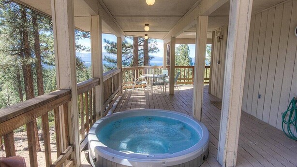 A hot tub on a wooden deck with a view of trees and mountains. - Hot Tub | Lake Views | Poker | Deck | BBQ (South Lake Tahoe)