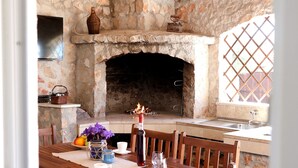 Una chimenea de piedra rústica con techo de madera y un área de comedor con sillas y mesa de madera.
