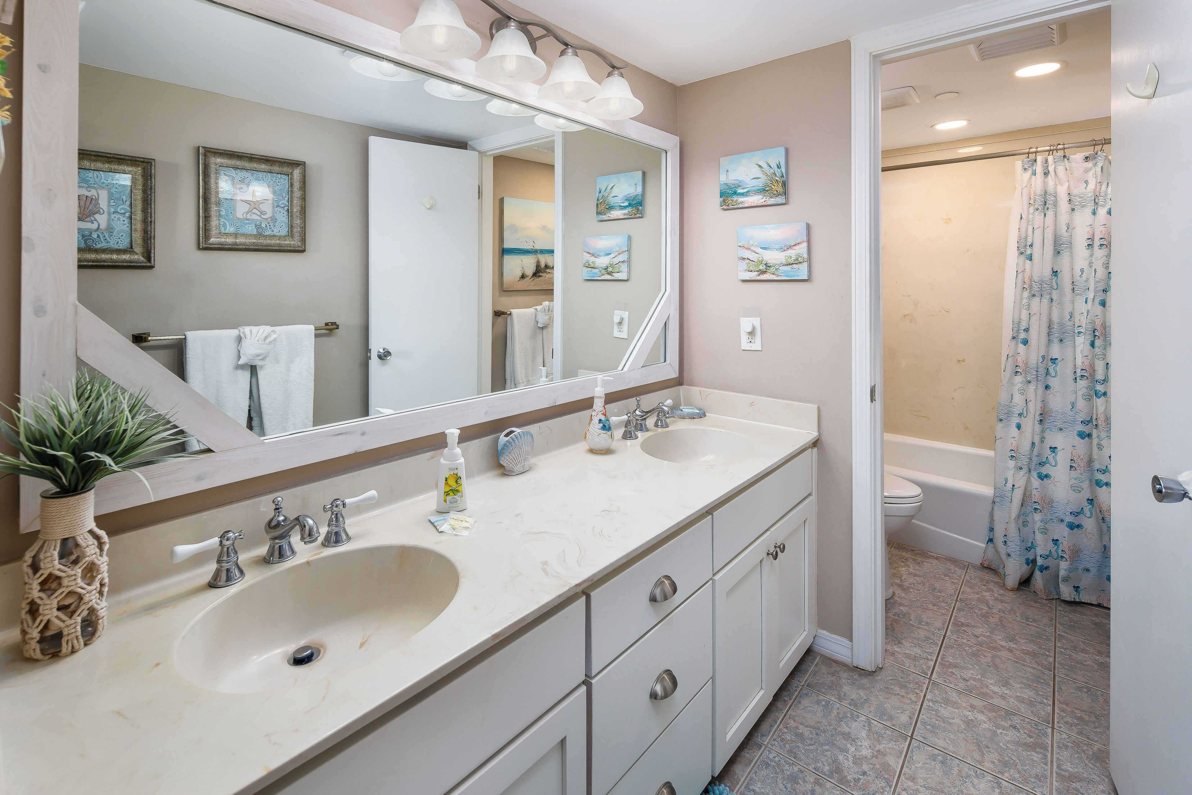 A bathroom with two sinks, a large mirror, and a shower.