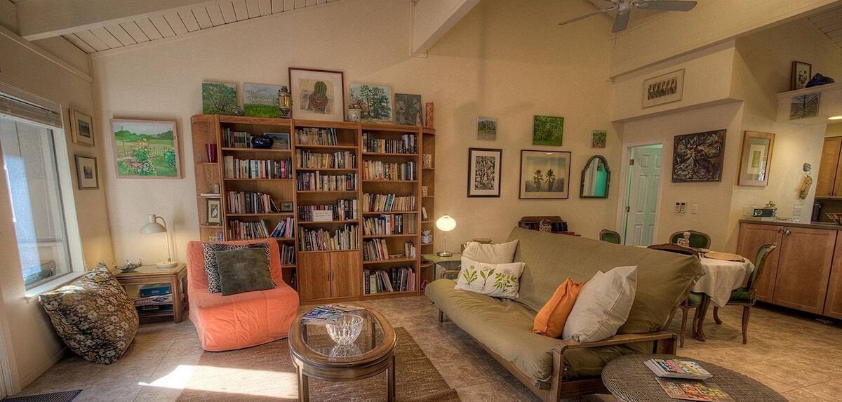 A cozy living room with a sofa, a coffee table, and a bookshelf filled with books.