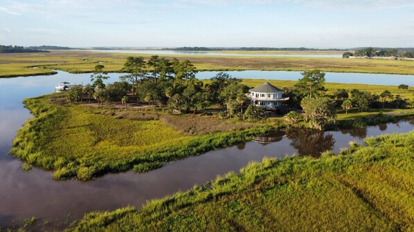 A house surrounded by water and greenery, with a clear view of the surrounding landscape.