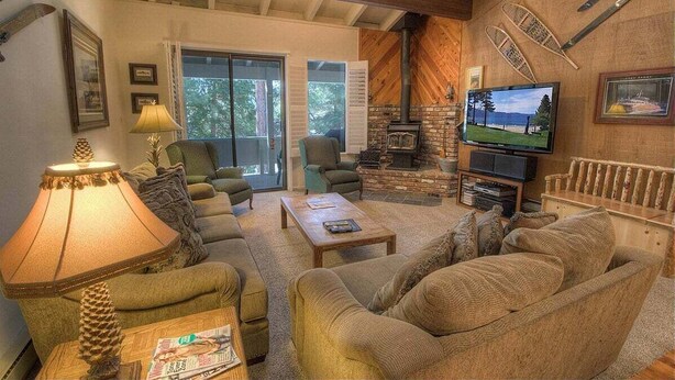 Una sala de estar acogedora con chimenea, asientos cómodos, un televisor y un ventanal grande.
