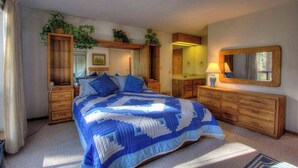 Ein Schlafzimmer mit einem großen Bett, einem hölzernen Schminktisch, Nachttischen und einem Spiegel.
