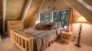 Una camera da letto mansardata accogliente con un letto di legno, un comodino e una lampada.