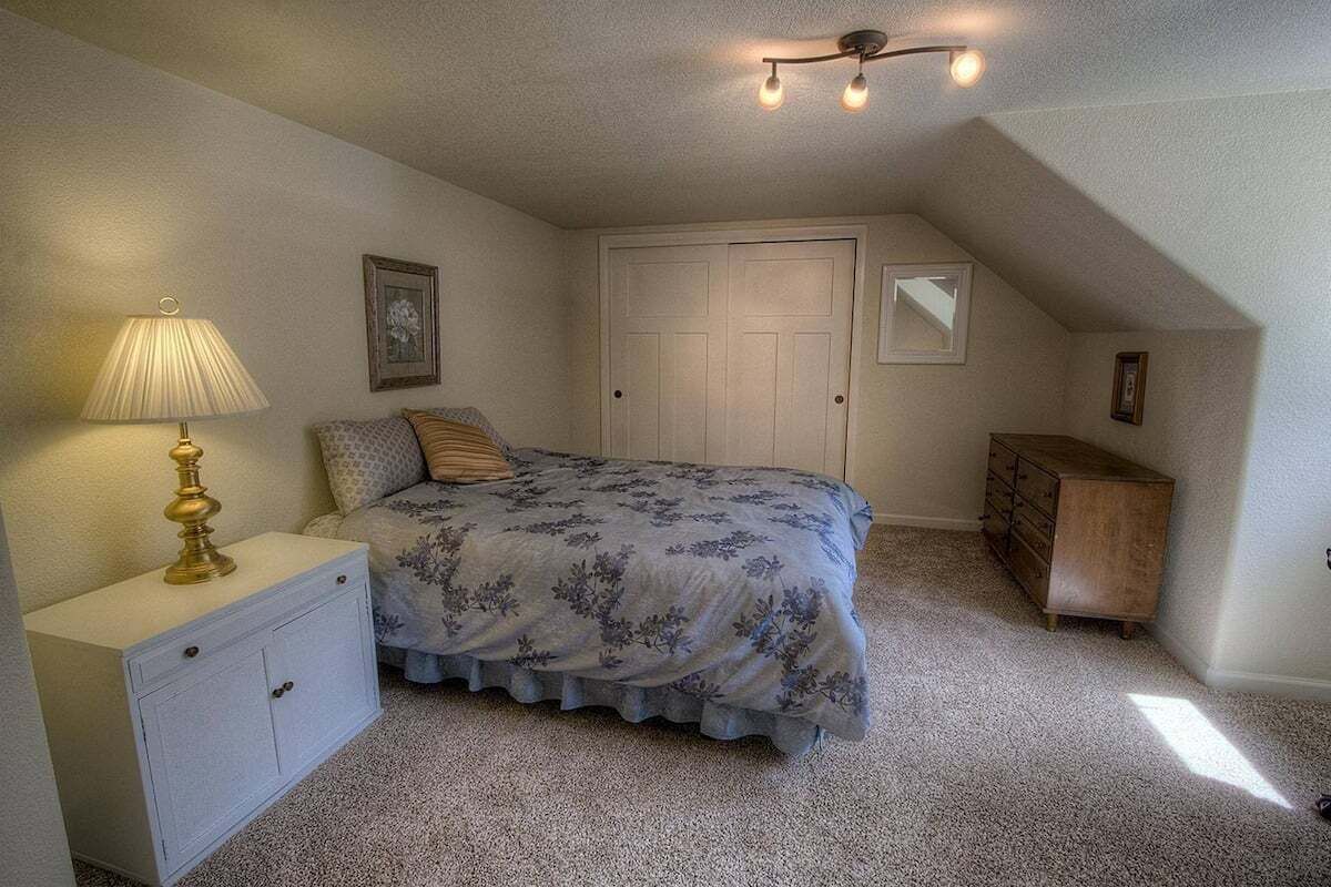 A bedroom with a bed, nightstand, dresser, and a ceiling light fixture.