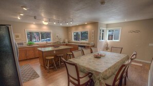 A spacious kitchen with wooden cabinets, a central island, and a dining area with a table and chairs.