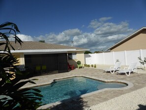 Patio trasero con piscina, zona de barbacoa y mobiliario de exterior.