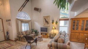 Una sala acogedora con dos sofás, un televisor y un mueble de madera.