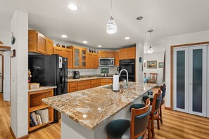 Una cocina moderna con armarios de madera, un refrigerador negro, un microondas y una encimera de granito.
