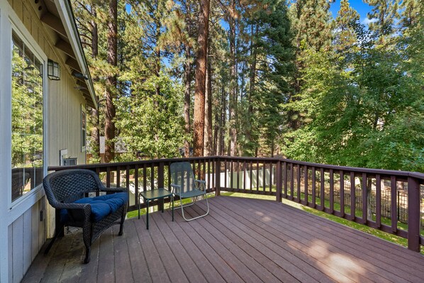 A wooden deck with a railing, two chairs, and a table. - Hot Tub | Deck | BBQ | Backyard (South Lake Tahoe)