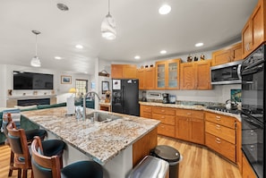 A modern kitchen with granite countertops, wooden cabinets, a stainless steel refrigerator, and a built-in oven. - Hot Tub | Deck | BBQ | Backyard (South Lake Tahoe)