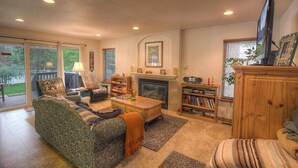 Una sala de estar acogedora con chimenea, un sofá, una mesa de centro y una televisión.