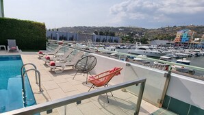 A rooftop pool area with lounge chairs and a view of a marina.