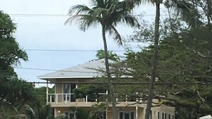 Un bâtiment à deux étages, doté d’un toit plat, entouré de verdure et bordé par un plan d’eau.