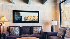Una sala de estar acogedora con dos sofás de cuero, una mesa de centro de madera y una obra de arte de piedra en la pared.