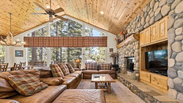 A cozy living room with leather sofas, a stone fireplace, and a large TV.