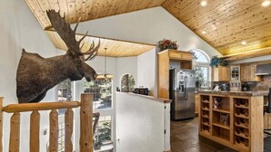 A modern kitchen with wooden cabinets, a built-in wine rack, and a large deer head mounted on the wall.