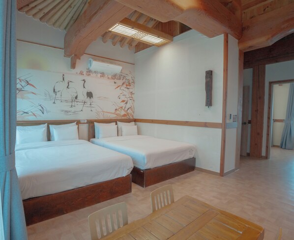 Habitación de hotel con dos camas, techo de madera, un mural en la pared y una mesa de madera.