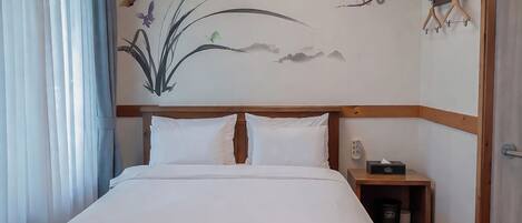 A hotel room with a bed, a nightstand with a lamp, and a wall with a floral mural.