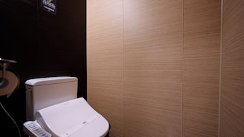 Et moderne badeværelse med toilet, håndtørrer og kontrolpanel.