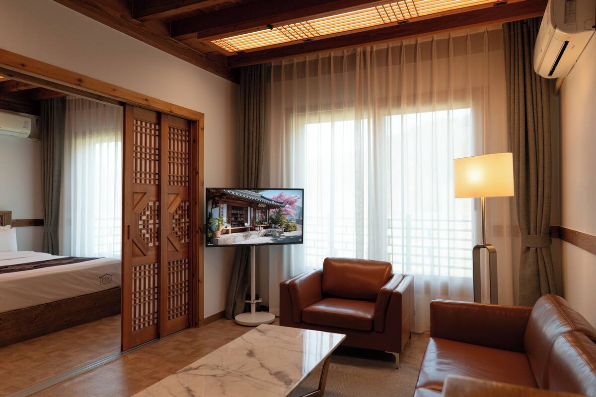 Ein Hotelzimmer mit einem Bett, einem Fernseher, einem Sofa, einem Couchtisch und einer Schiebetür.
