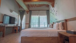 Quarto com cama de madeira, escrivaninha com televisão e janela com cortinas.