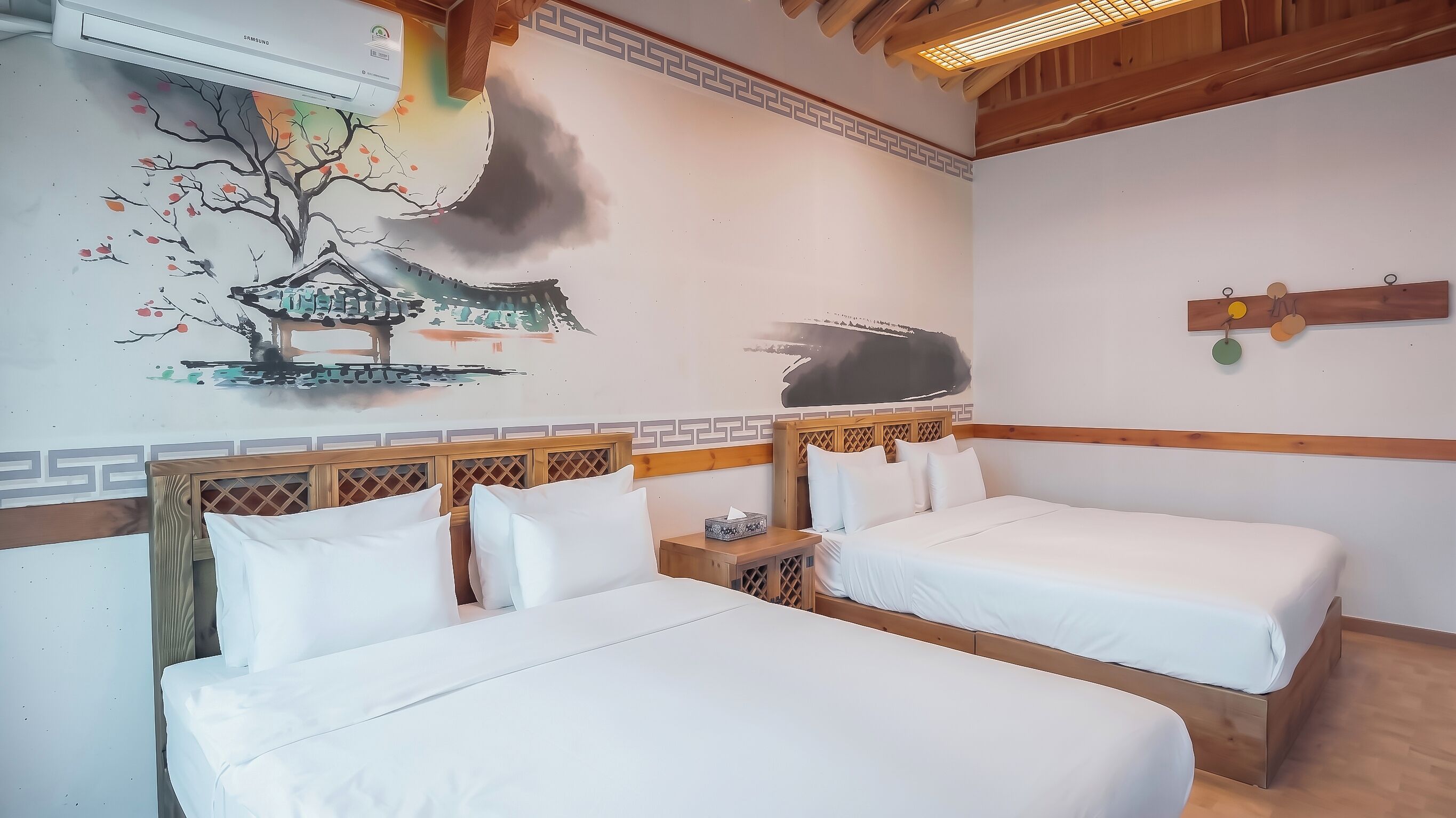 A hotel room with two beds, a wall mural, a wooden headboard, and a ceiling fan.
