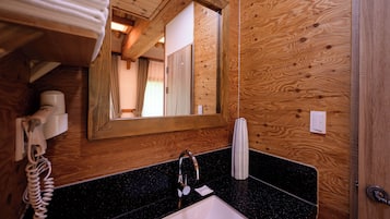 Un interior de madera con un lavabo de encimera negra, un espejo, un perchero para toallas y un teléfono.